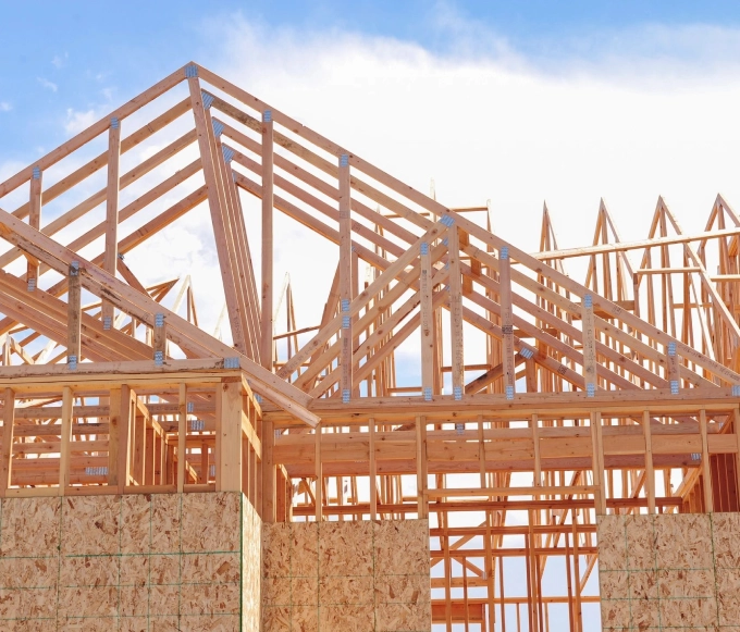 A building under construction with wooden beams and roof.