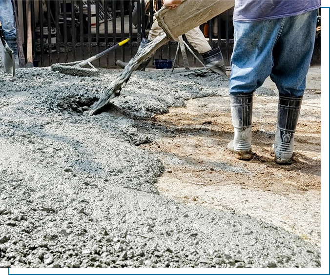 A person is pouring cement on the ground.