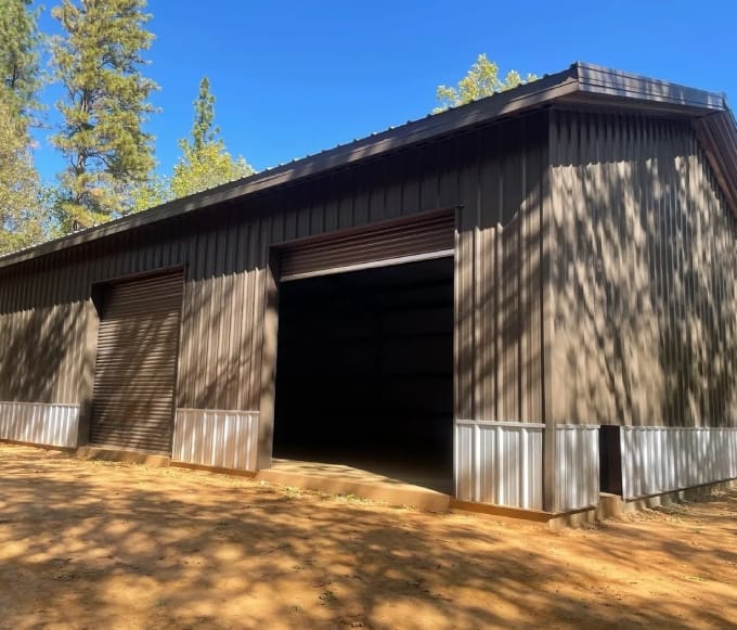 A large barn with a door open in the middle of it.